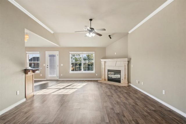 unfurnished living room featuring a tiled fireplace, crown molding, dark hardwood / wood-style flooring, and ceiling fan