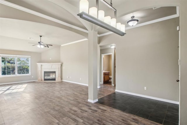 unfurnished living room featuring ornamental molding, ceiling fan, a fireplace, dark hardwood / wood-style floors, and lofted ceiling