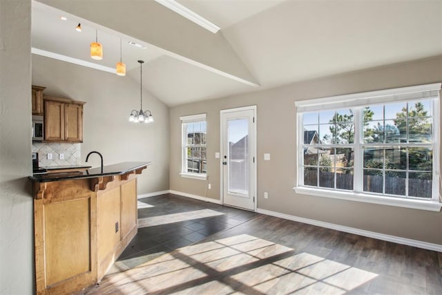 kitchen featuring a breakfast bar, an inviting chandelier, hanging light fixtures, vaulted ceiling, and decorative backsplash