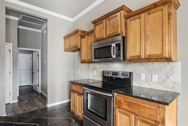 kitchen with dark stone counters, dark tile patterned flooring, decorative backsplash, ornamental molding, and stainless steel appliances