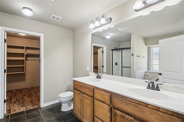 bathroom with tile patterned floors, vanity, toilet, and a shower with shower door