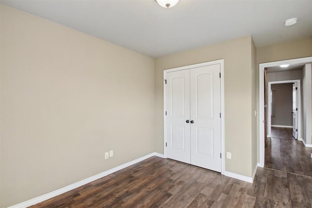 unfurnished bedroom with dark hardwood / wood-style flooring and a closet