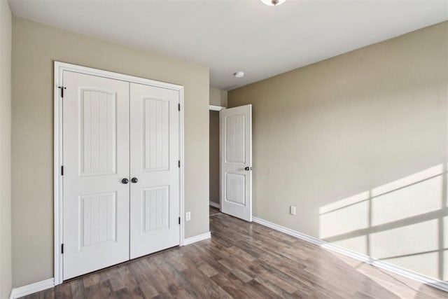 unfurnished bedroom with dark hardwood / wood-style flooring and a closet