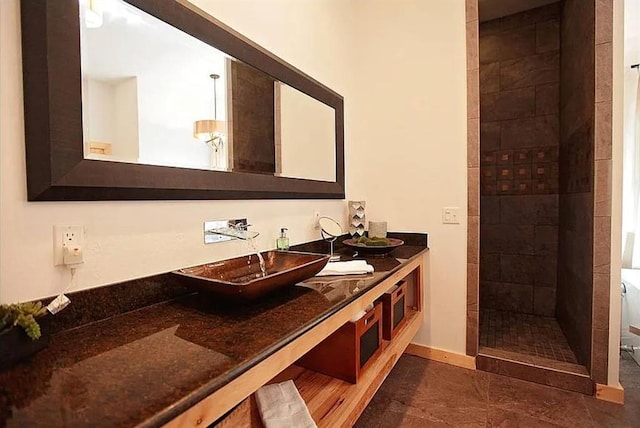 bathroom featuring a tile shower, tile patterned flooring, and vanity