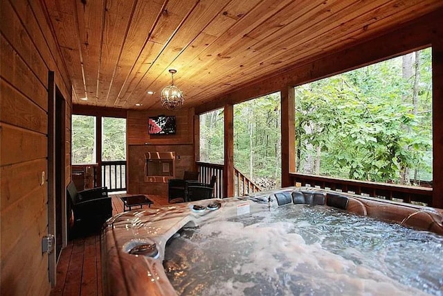 sunroom with a hot tub, wood ceiling, and an inviting chandelier