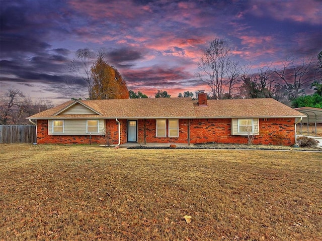 ranch-style house featuring a carport and a lawn