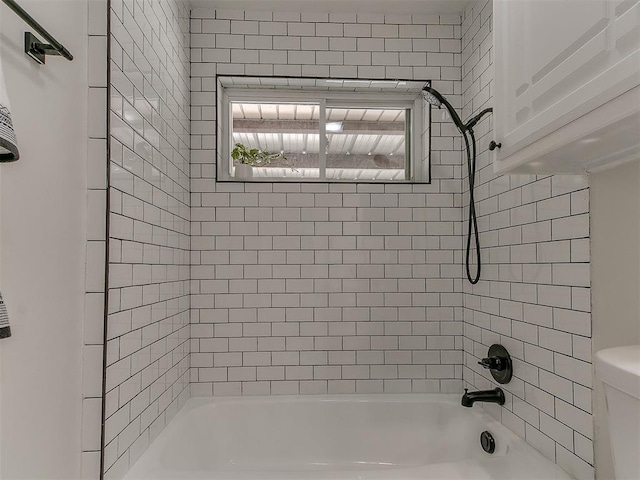 bathroom featuring tiled shower / bath combo and toilet