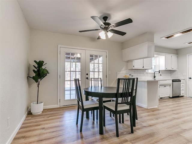 dining room featuring french doors, light wood-type flooring, ceiling fan, and sink