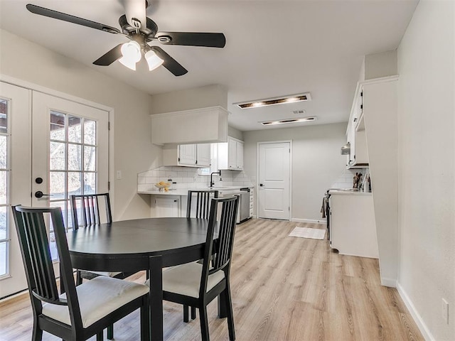 dining area with ceiling fan, light hardwood / wood-style floors, sink, and french doors