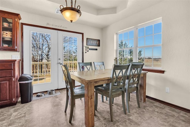 dining area with french doors and a raised ceiling