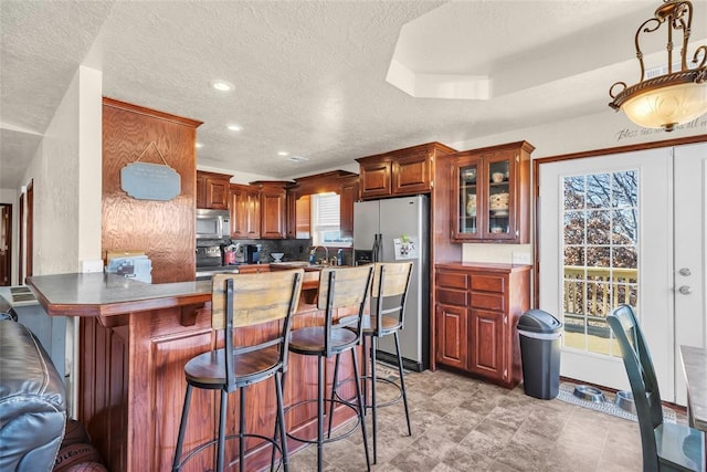 kitchen featuring a breakfast bar area, kitchen peninsula, a healthy amount of sunlight, and appliances with stainless steel finishes