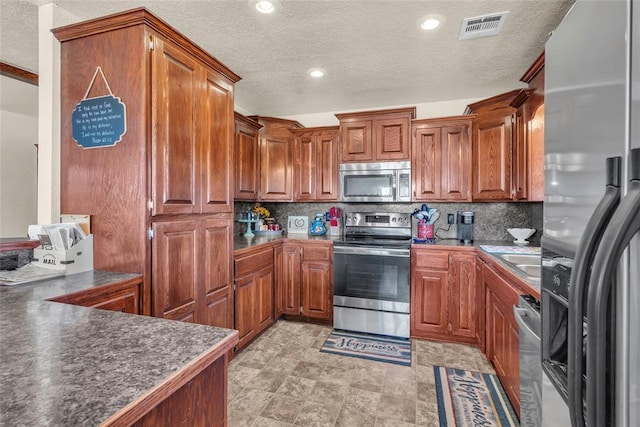 kitchen featuring appliances with stainless steel finishes, backsplash, a textured ceiling, and sink