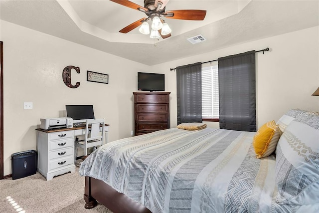 carpeted bedroom with a tray ceiling and ceiling fan