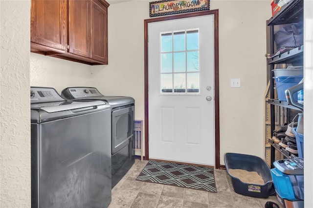 clothes washing area with washer and clothes dryer and cabinets