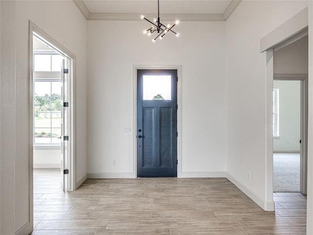 foyer entrance with crown molding, a healthy amount of sunlight, and an inviting chandelier