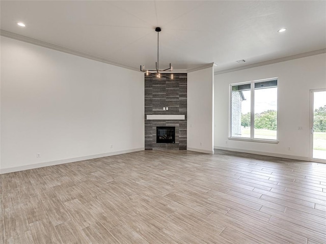 unfurnished living room featuring a fireplace, ornamental molding, and a notable chandelier