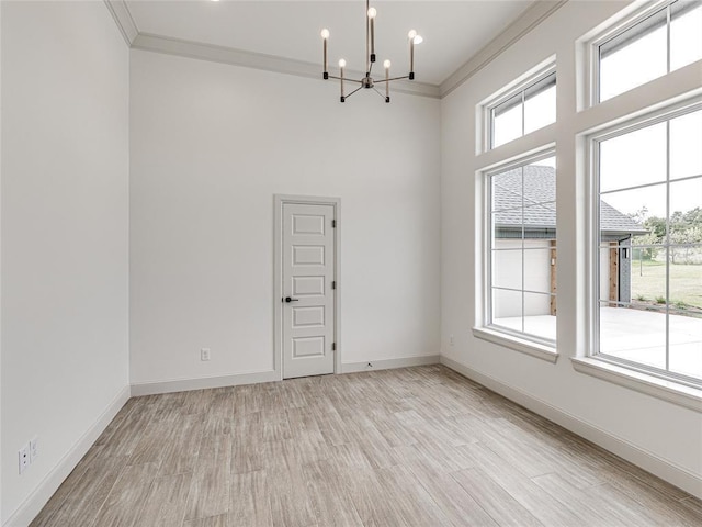 spare room featuring plenty of natural light, a chandelier, light wood-type flooring, and ornamental molding