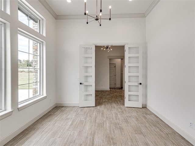 empty room with a notable chandelier, a healthy amount of sunlight, and ornamental molding