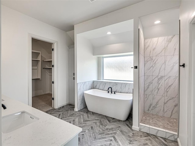 bathroom featuring vanity, separate shower and tub, and tile walls