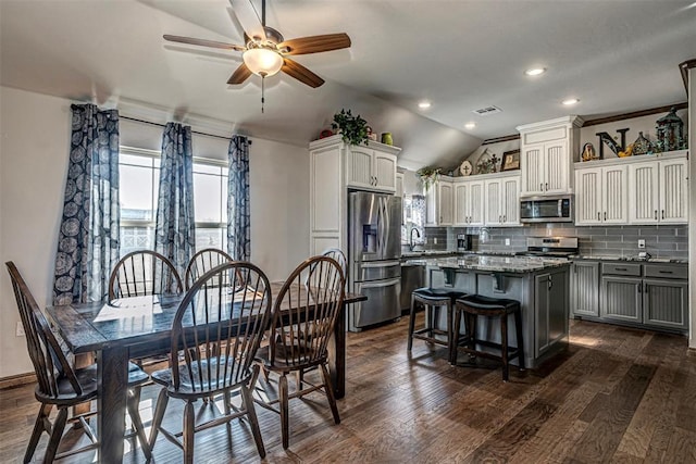 dining area featuring dark hardwood / wood-style floors, vaulted ceiling, ceiling fan, and sink