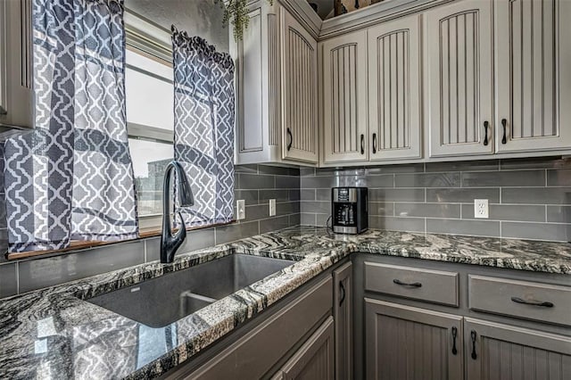 kitchen featuring backsplash, sink, and dark stone counters