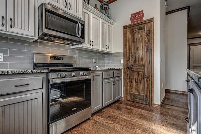 kitchen with gray cabinets, tasteful backsplash, stainless steel appliances, and dark wood-type flooring