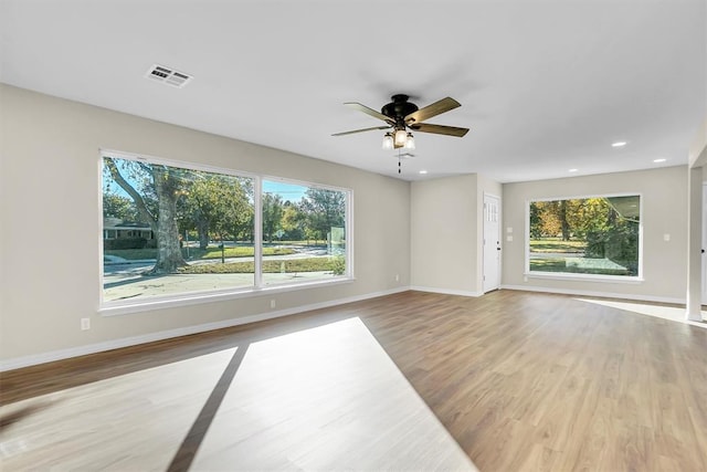 unfurnished room featuring hardwood / wood-style floors, ceiling fan, and a healthy amount of sunlight