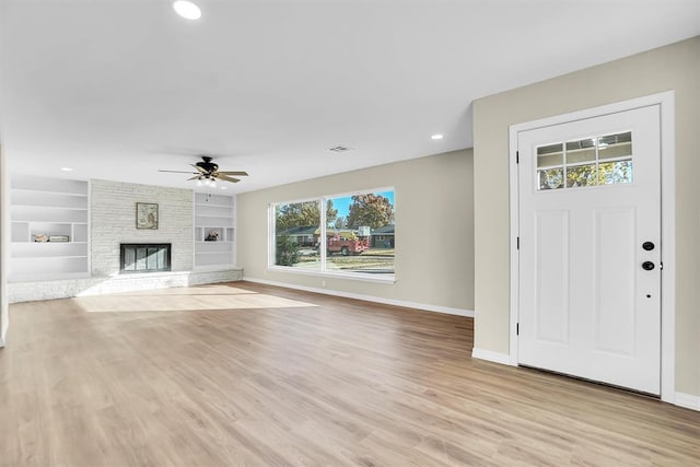 entrance foyer with light hardwood / wood-style flooring, ceiling fan, and a stone fireplace