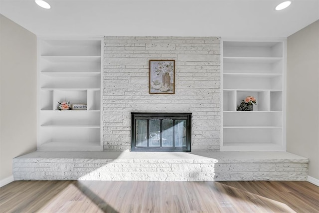 living room with a fireplace, wood-type flooring, and built in features