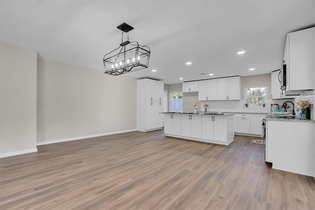 kitchen featuring pendant lighting, a kitchen island, white cabinetry, and light hardwood / wood-style flooring