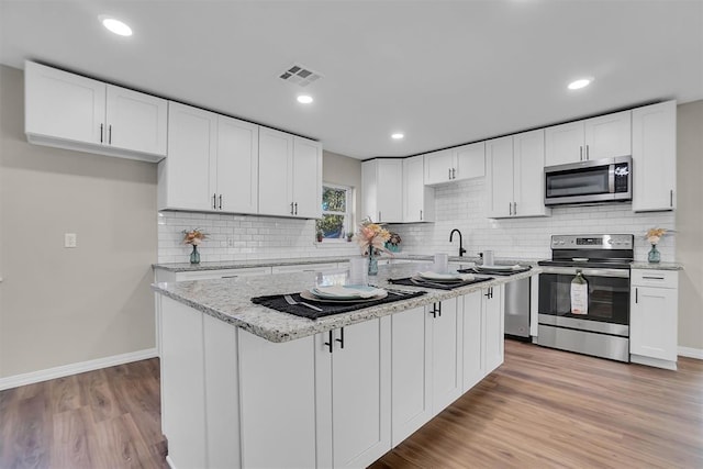 kitchen featuring white cabinetry, a center island, light hardwood / wood-style floors, and appliances with stainless steel finishes