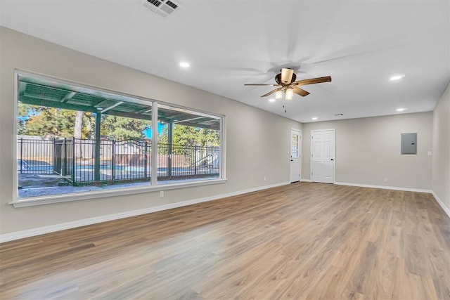 spare room featuring wood-type flooring, electric panel, and ceiling fan