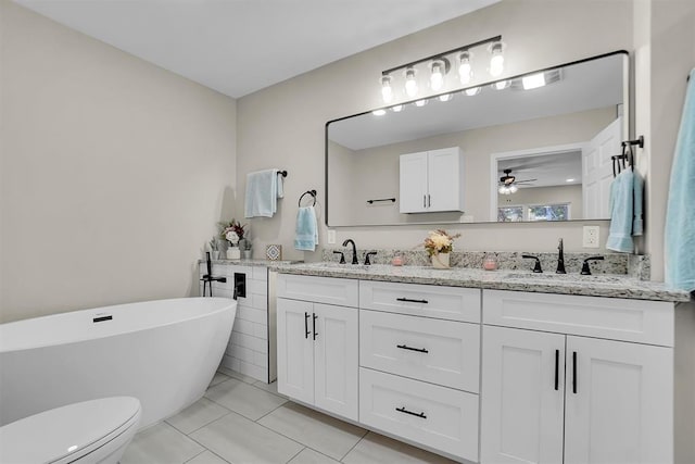 bathroom with vanity, tile patterned flooring, ceiling fan, a washtub, and toilet