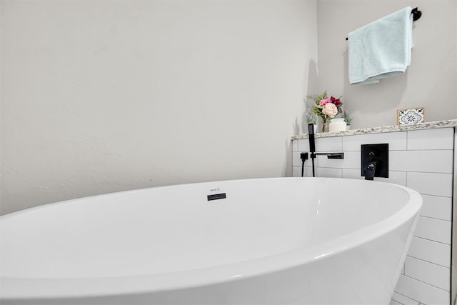 bathroom with a washtub and tile walls