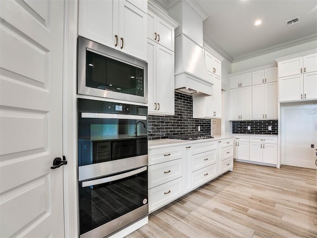 kitchen featuring white cabinets, ornamental molding, and stainless steel appliances