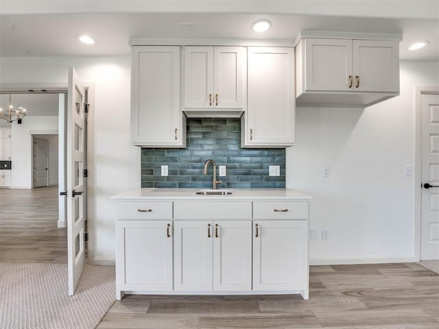 kitchen with light hardwood / wood-style flooring, white cabinetry, sink, and tasteful backsplash