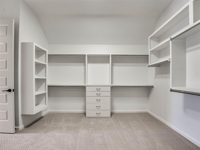 walk in closet with light colored carpet and lofted ceiling