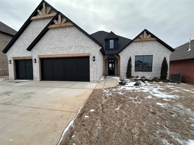 view of front of house featuring an attached garage, central AC, concrete driveway, and brick siding