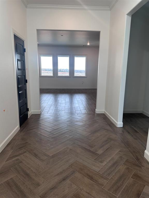 empty room featuring ornamental molding and baseboards