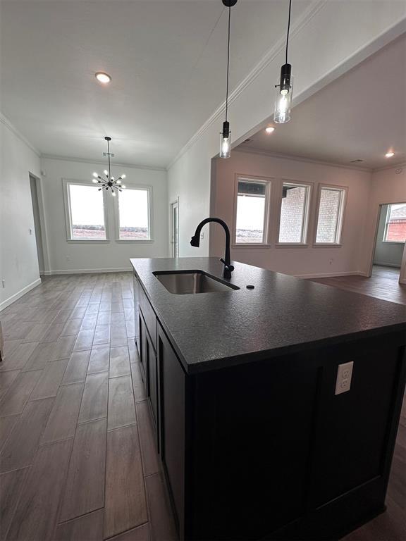 kitchen featuring open floor plan, a sink, a center island with sink, and decorative light fixtures