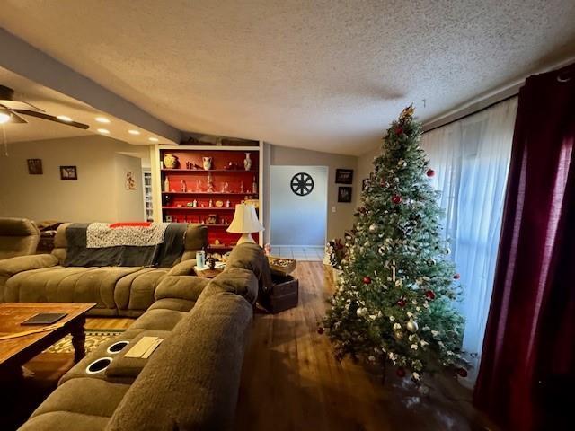 living room with hardwood / wood-style floors, a textured ceiling, ceiling fan, and lofted ceiling