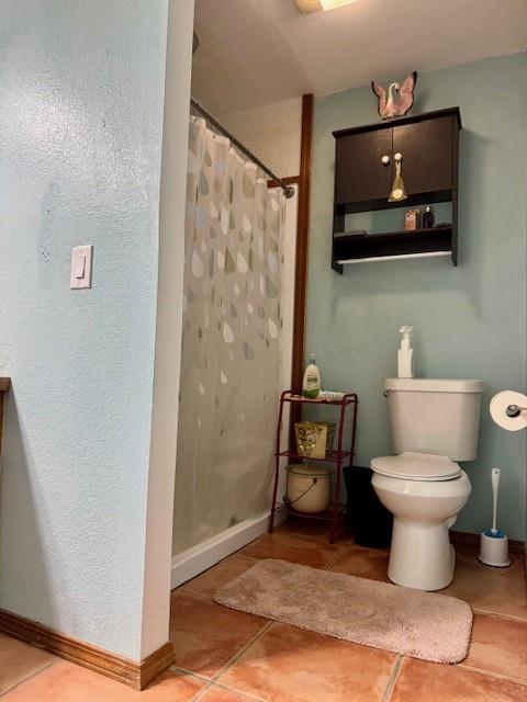 bathroom featuring a shower with shower curtain, toilet, and tile patterned floors