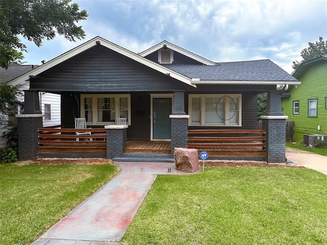 bungalow with a front lawn, cooling unit, and covered porch