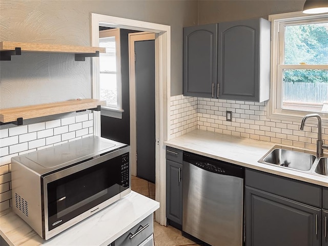 kitchen with tasteful backsplash, gray cabinets, sink, and appliances with stainless steel finishes