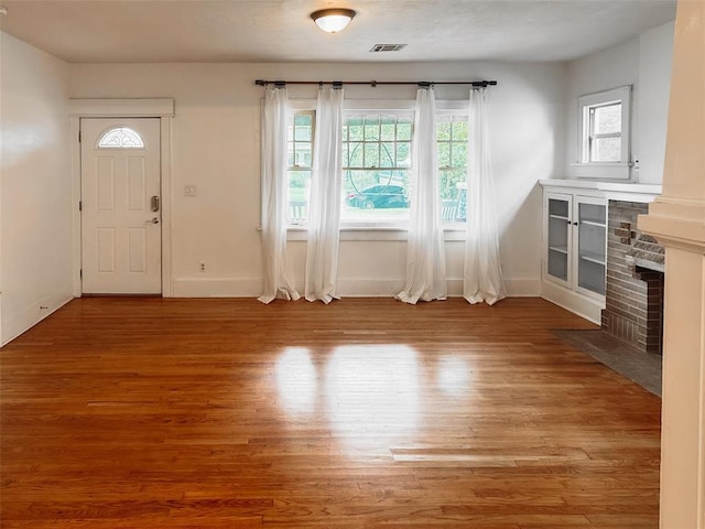 unfurnished living room featuring hardwood / wood-style flooring and a brick fireplace