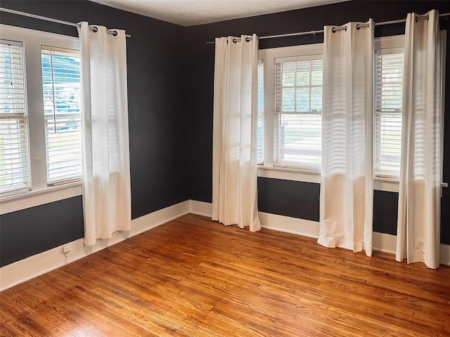 spare room with plenty of natural light and wood-type flooring