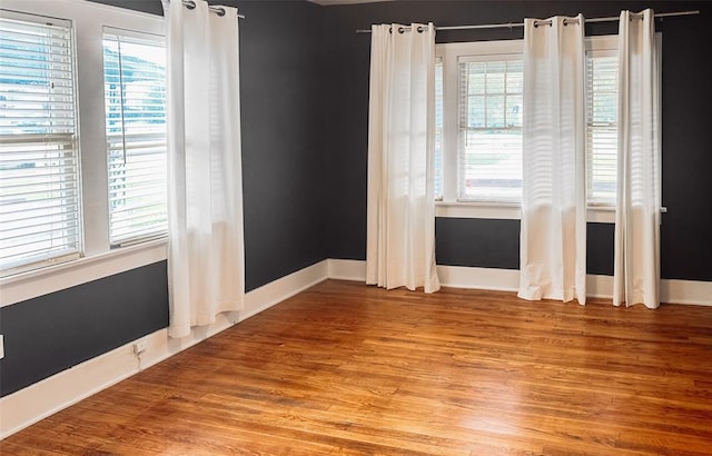 empty room featuring a healthy amount of sunlight and hardwood / wood-style flooring