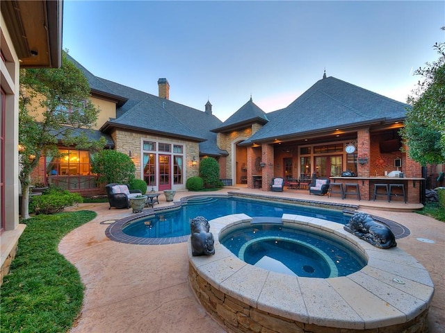 view of swimming pool featuring an in ground hot tub, exterior bar, and a patio