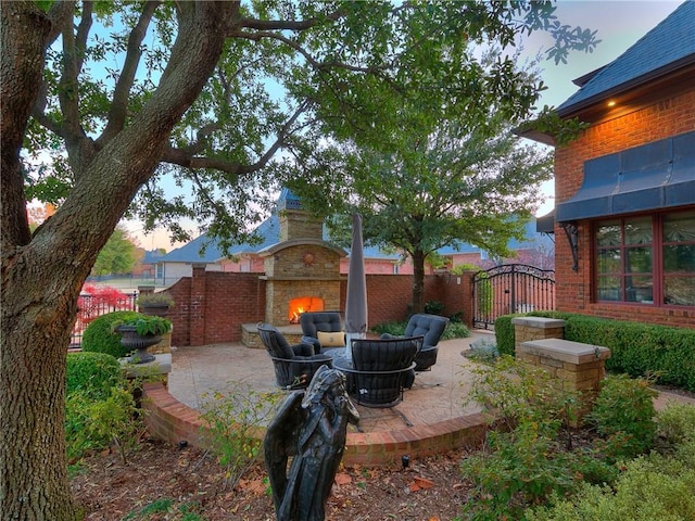 yard at dusk featuring a patio area and an outdoor stone fireplace