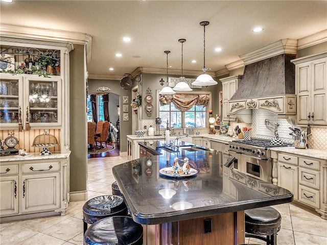 kitchen featuring dark stone countertops, a kitchen island, a kitchen bar, and premium range hood